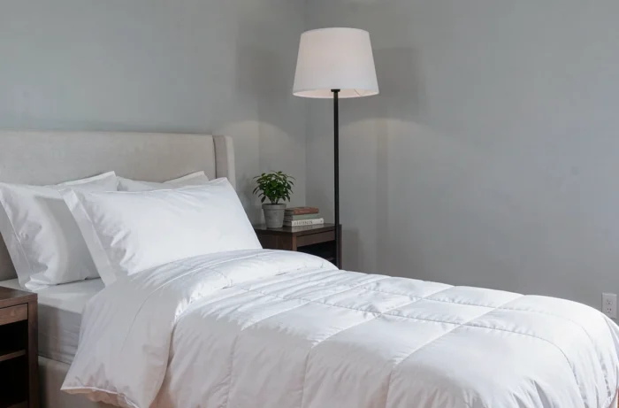 Lampadaire noir élégant à abat-jour blanc dans une chambre moderne minimaliste avec literie en coton blanc